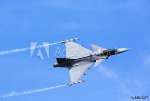 Afbeeldingen van Modern jet fighter flying against a blue sky White smoke trail